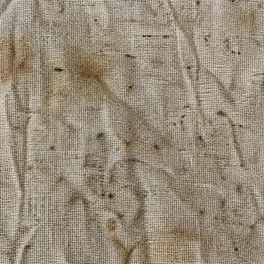 Close-up of dusty, stained beige curtain fabric before professional cleaning